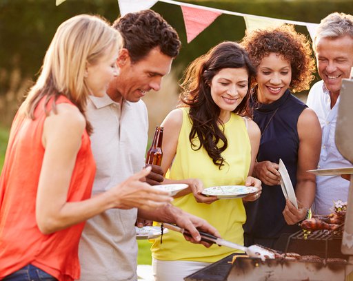 mature friends enjoying outdoor summer barbeque in garden